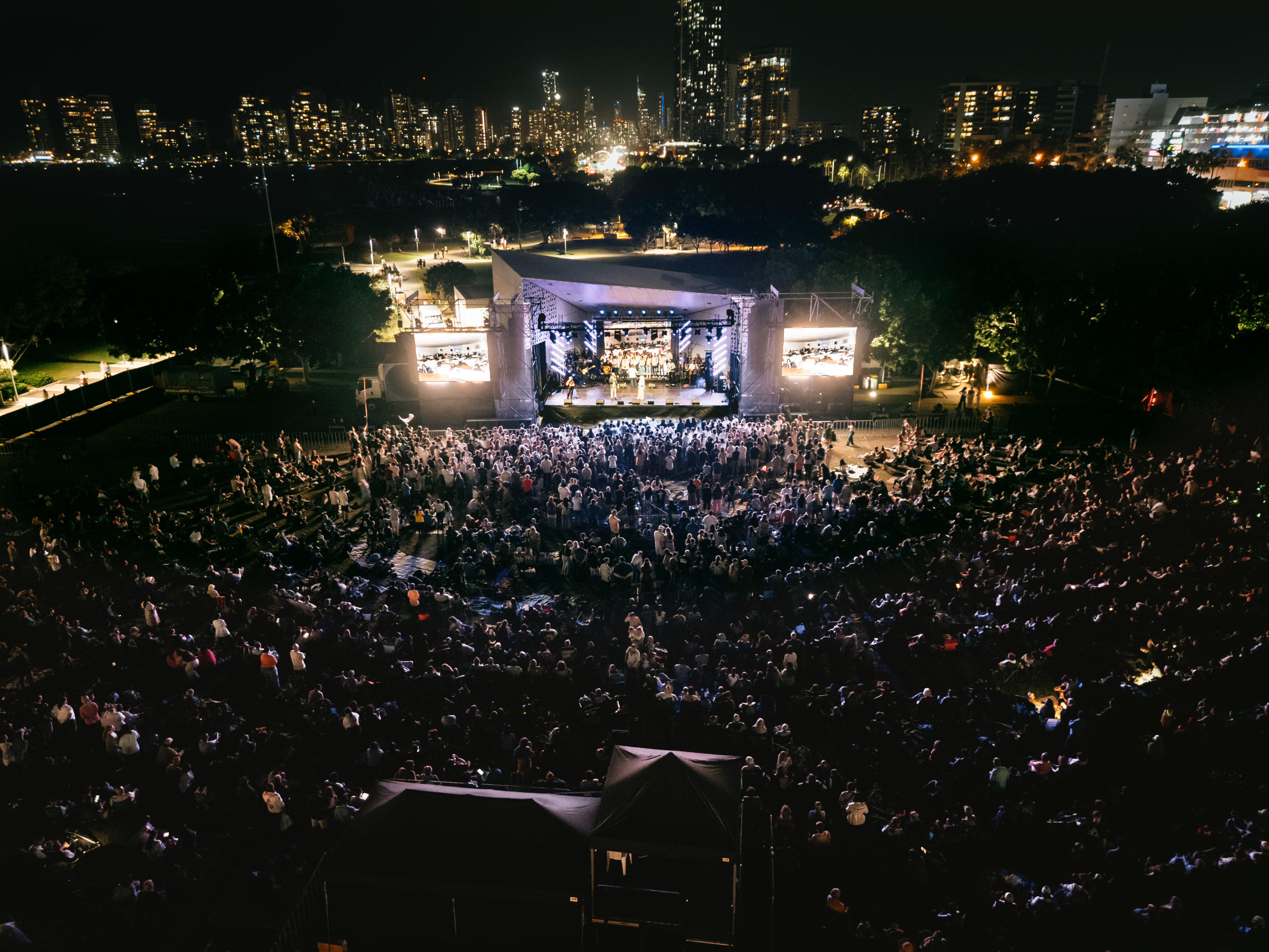 Aerial view of the Easter United crowd gathered before the stage at night, with the Gold Coast skyline behind